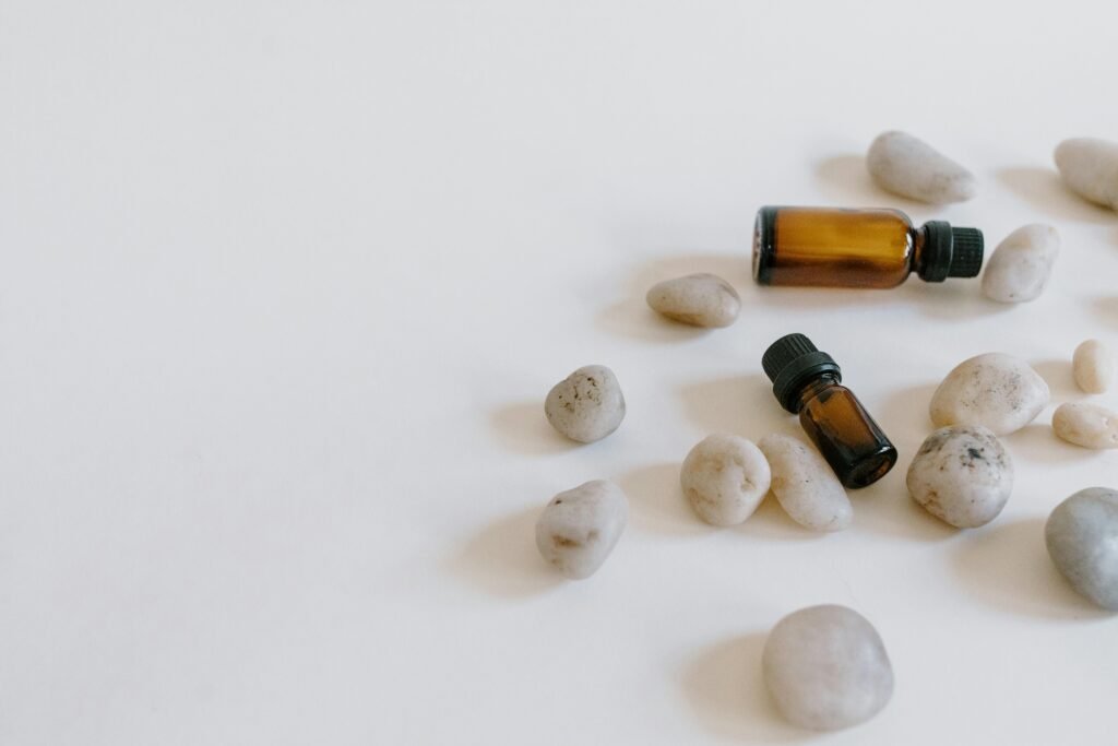 Minimalist arrangement of essential oil bottles surrounded by stones on a light background.